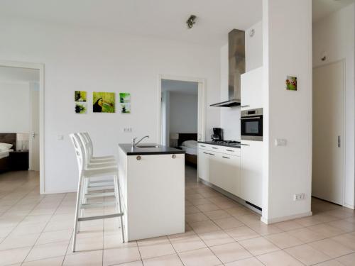 a white kitchen with a white counter and a stool at Prime villa with terrace and jetty in Zeewolde
