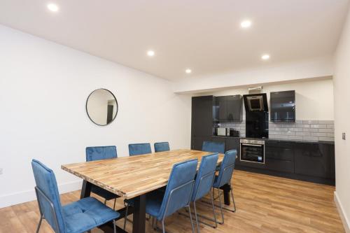 a kitchen and dining room with a wooden table and blue chairs at Concert Square Apartments By Happy Days in Liverpool