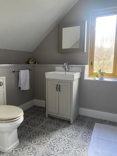 a bathroom with a sink and a toilet and a window at Arisaig Holiday Apartment in Arisaig