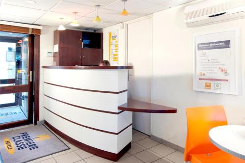 a bar in a restaurant with a table and a chair at Premiere Classe Dunkerque Est Armbouts Cappel in Armbouts-Cappel