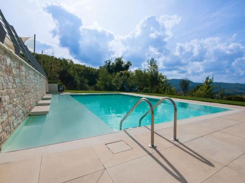 einen Pool mit einer Steinmauer und blauem Wasser in der Unterkunft Belvilla by OYO Ca Luigi in Acqualagna