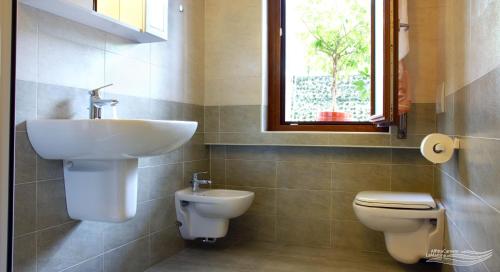 bagno con lavandino, servizi igienici e finestra di Affittacamere La Martina a Vigano San Martino