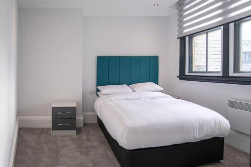 a bedroom with a large bed with a green headboard at Cavern Quarter apartments by The Castle Collection in Liverpool