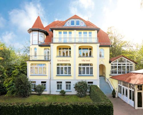 a large white house with a red roof at Strandresidenz Villa Verdi in Kühlungsborn