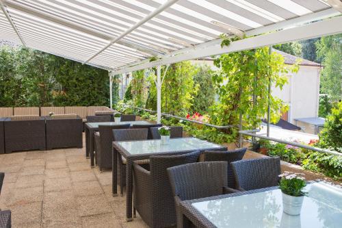 a patio with tables and chairs under a white pergola at Stadthotel Freiburg Kolping Hotels & Resorts in Freiburg im Breisgau