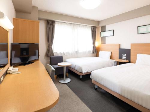 a hotel room with two beds and a flat screen tv at Comfort Hotel Himeji in Himeji