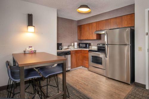 a kitchen with a table and a stainless steel refrigerator at Sonesta ES Suites Baltimore BWI Airport in Linthicum Heights