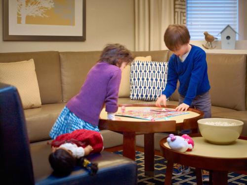 a boy and a girl playing a game in a living room at Sonesta ES Suites Baltimore BWI Airport in Linthicum Heights
