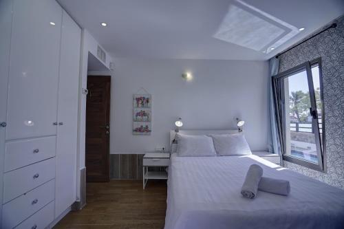 ein weißes Schlafzimmer mit einem Bett und einem Fenster in der Unterkunft Villa Pomela By Sun And View in Eilat