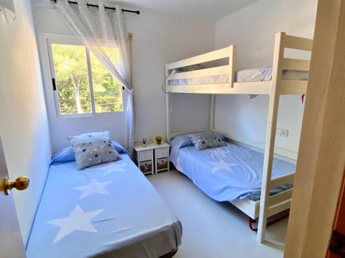 1 Schlafzimmer mit 2 Etagenbetten und einem Fenster in der Unterkunft Acogedor apartamento con piscina en tamariu in Tamariu