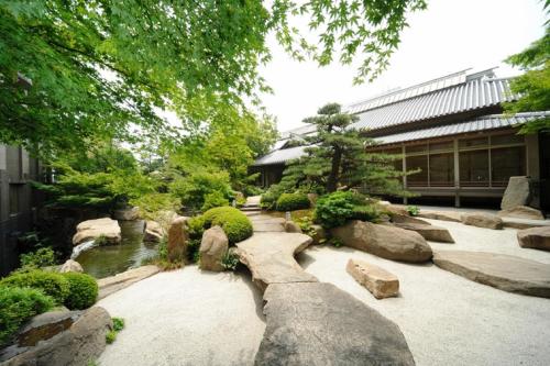 a garden with rocks and a pond in front of a building at Imabari Kokusai Hotel in Imabari