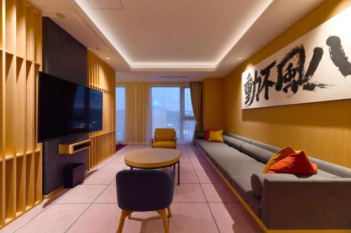 a living room with a couch and a tv at The Centurion Hotel & Spa Classic Izumo in Izumo