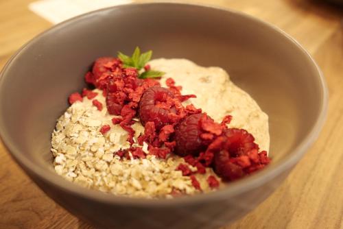 a bowl of food with raspberries andinoa on a table at Seehotel Hartung & Ferienappartements in Füssen