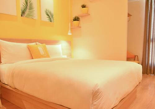 a bedroom with a white bed with plants on the wall at Bloom - Golf Course Road in Gurgaon