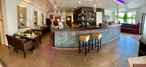 ein Restaurant mit einer Bar und einigen Tischen und Stühlen in der Unterkunft Boutique Hotel Goldene Henne in Wolfsburg
