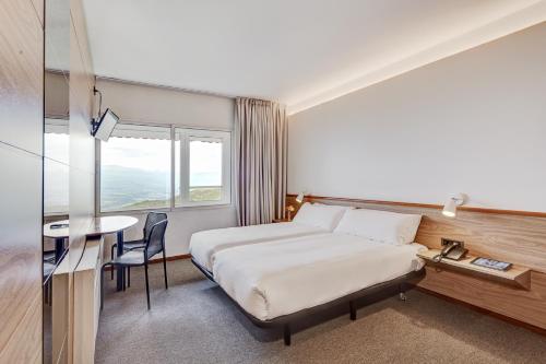 une chambre d'hôtel avec un lit et une table dans l'établissement Alp Hotel Masella, à La Masella