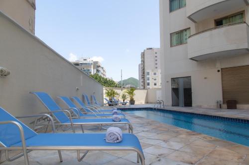 a group of blue chairs sitting next to a swimming pool at Lobie Botafogo Privilege in Rio de Janeiro