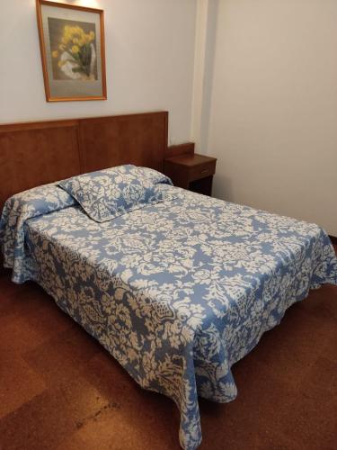 a bedroom with a bed with a blue comforter at Hotel Herbiña in Cambados