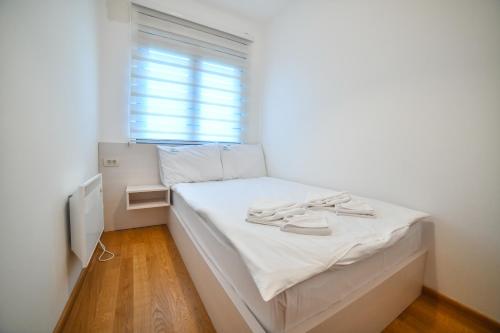 a bedroom with a bed with white sheets and a window at Balkan Hill Zlatibor in Zlatibor
