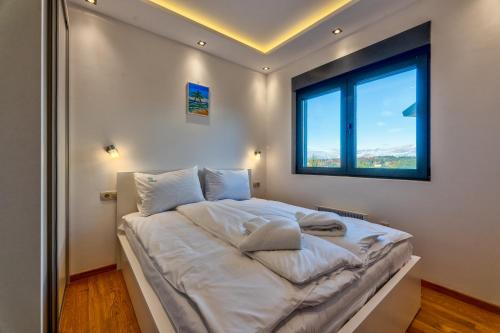 a bedroom with a large white bed with a window at Balkan Hill Zlatibor in Zlatibor
