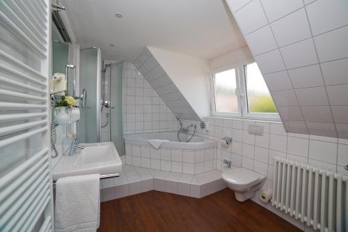 a bathroom with a sink and a tub and a toilet at Stadthotel Freiburg Kolping Hotels & Resorts in Freiburg im Breisgau