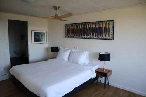 een slaapkamer met een wit bed en een plafondventilator bij Bed & Coffee Maricoweg in Den Burg