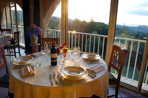 a table with plates and utensils on a table on a balcony at Toscana Wellness Resort in Arcidosso