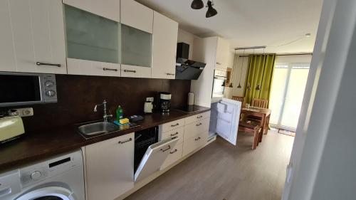 una cucina con armadi bianchi, lavandino e lavastoviglie di Lieblingsplatz im Küstenwald Graal-Müritz a Gelbensande