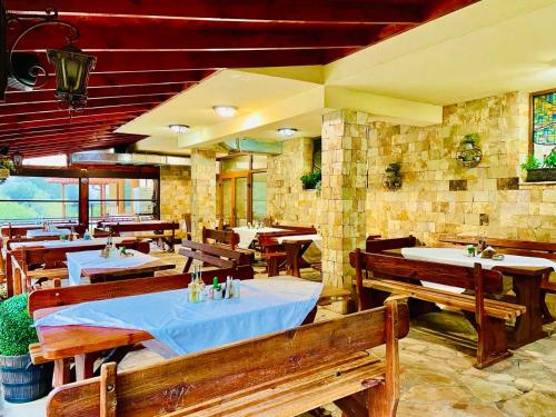 a restaurant with tables and benches in a building at Family Hotel Gorski Kut in Rilski Manastir