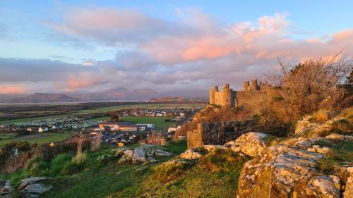 a castle on a hill with a town in the background at Y Branwen Restaurant & Rooms - Adult Only and Dog Friendly in Harlech