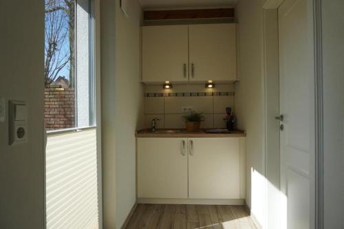 a kitchen with white cabinets and a sink and a window at Ferienwohnungen Heideidylle in Amelinghausen