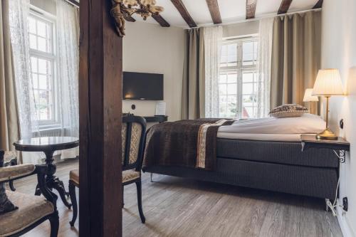a bedroom with a bed and a desk and windows at Hotell Hamngatan 27 in Falkenberg