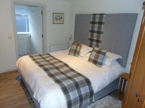 Un dormitorio con una cama con una manta a cuadros. en Dreamwood Cottage, Loch Lomond, Luxury Apartment., en Glasgow