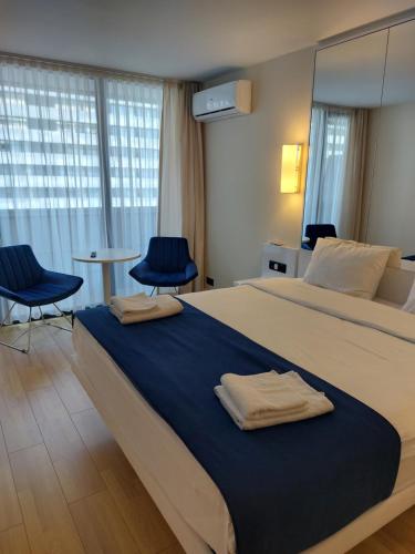 ein Schlafzimmer mit einem großen Bett mit zwei blauen Stühlen in der Unterkunft Twins tower orbi city in Batumi