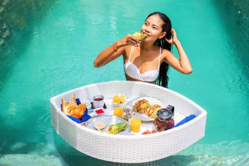 una mujer en el agua comiendo comida en el agua en Bali Mynah Villas Resort, en Jimbaran