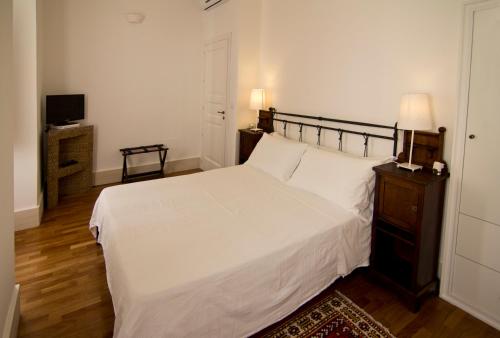 a bedroom with a white bed and a television at La Residenza del Reginale in Siracusa