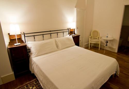 a bedroom with a white bed and a lamp and a chair at La Residenza del Reginale in Siracusa