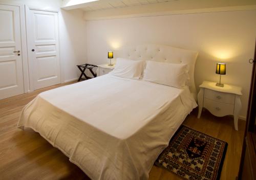 a bedroom with a white bed with two tables and two lamps at La Residenza del Reginale in Siracusa