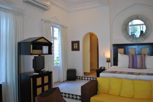 sypialnia z łóżkiem, krzesłem i lustrem w obiekcie Coco Ocean Resort & Spa w mieście Bijilo