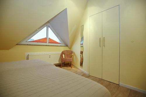 - une chambre mansardée avec un lit et une fenêtre dans l'établissement Residenz Seestern Wohnung 49, à Boltenhagen