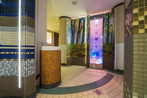 a bathroom with a walk in shower with trees on the wall at Residenz Seestern Wohnung 49 in Boltenhagen