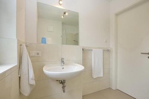 a white bathroom with a sink and a mirror at Feriendorf Am Mariannenweg Reethaus 14b in Boltenhagen