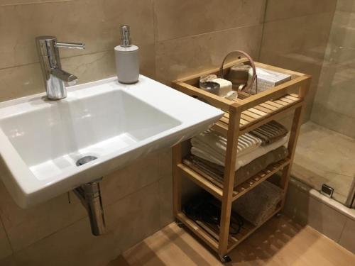 a bathroom with a sink and a shelf with towels at Apartamento Plaza de Los Naranjos Marbella in Marbella