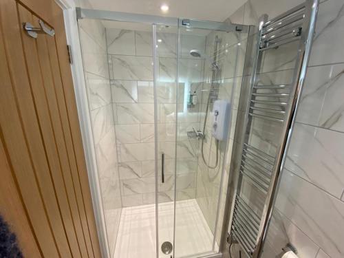 a shower with a glass door in a bathroom at Sweet Caroline - luxury studio stone’s throw from Mousehole harbour in Mousehole