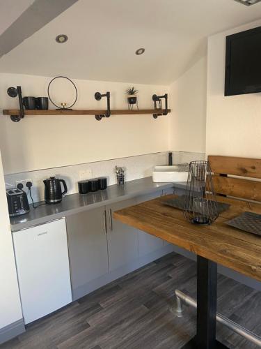 a kitchen with white cabinets and a wooden table at The Old Milking Parlour in Longton