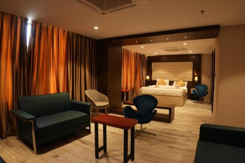 a hotel room with a bed and a couch and chairs at HOTEL OCEAN VISTA BAY in Visakhapatnam