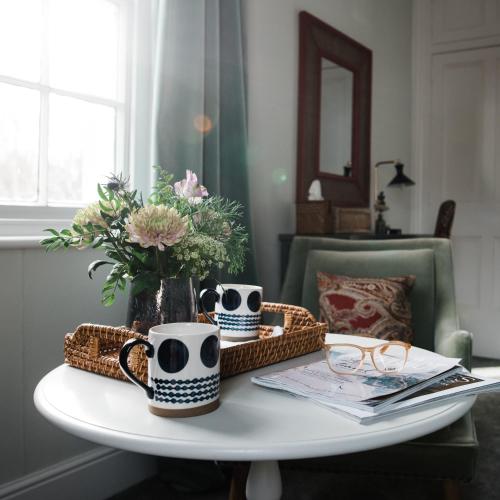a coffee table with two mugs and a basket of flowers at The Naight House in Gloucester