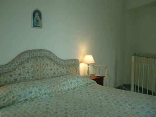 ラヴェッロにあるLa Clarissa Amalfi Dreamsのベッドルーム1室(ベッド1台、ランプ、壁の絵付)