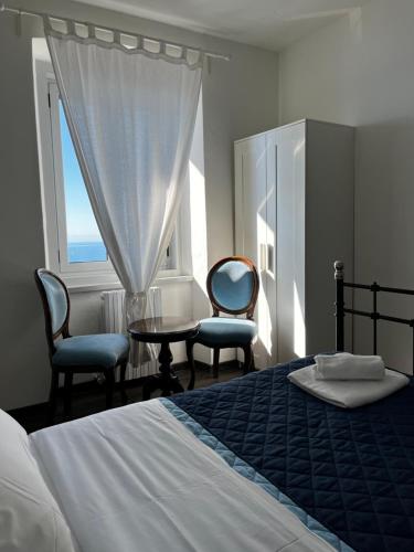 a bedroom with a bed and two chairs and a window at Villa Tergeste in Trieste