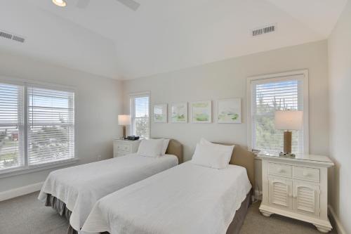 two beds in a white room with windows at The Sanderling in Duck